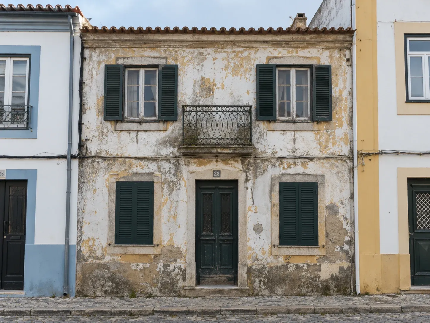 Fachada de casa tradicional portuguesa com o reboco perdido e a cantaria enegrecida