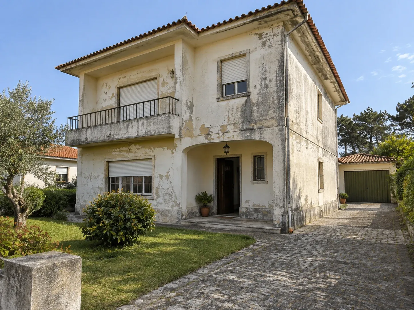 Fachada de moradia com varanda, com a tinta envelhecida e o paramento manchado