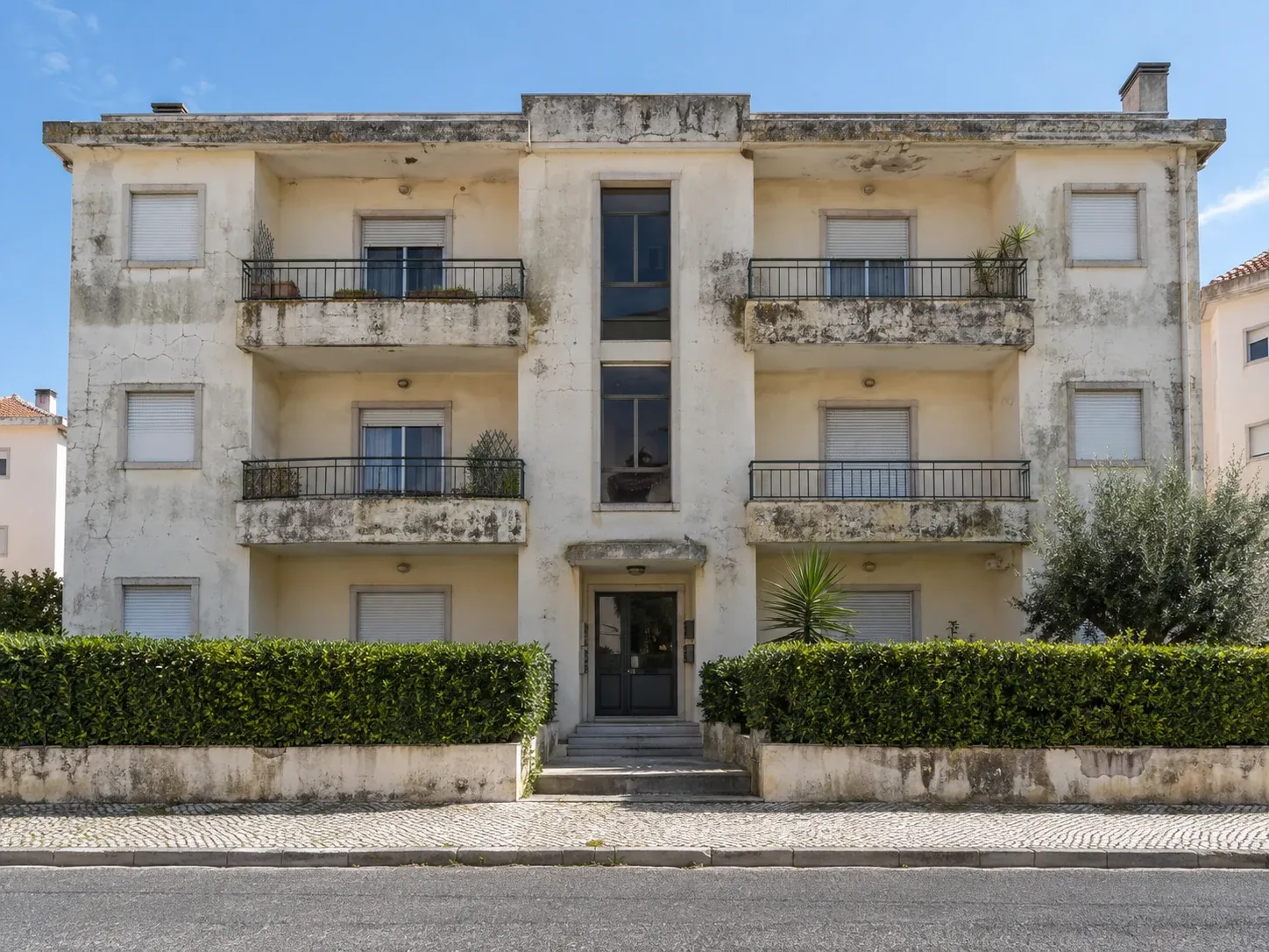 Fachada frontal de prédio com fissuras e algas no paramento