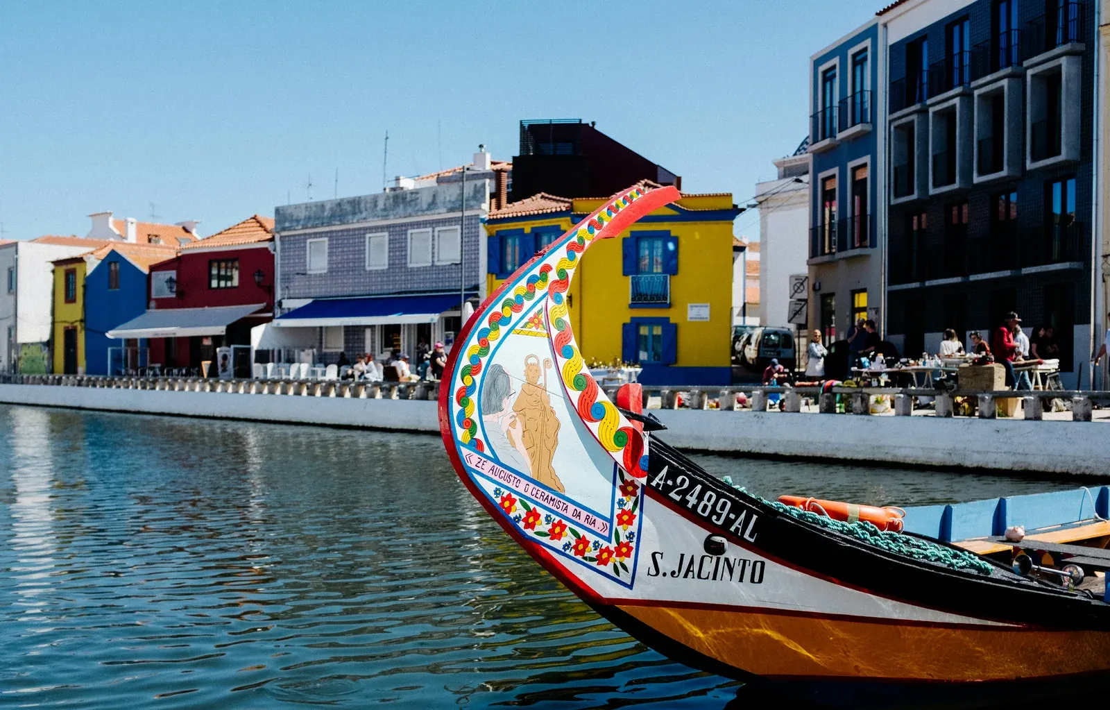 Moliceiro tradicional num canal de Aveiro, com fachadas coloridas ao fundo