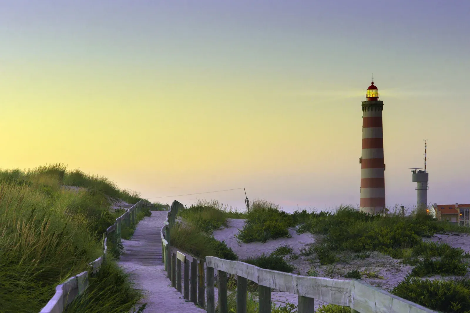 Farol da Barra às riscas vermelhas e brancas, junto às dunas e ao passadiço da Praia da Barra, na Gafanha da Nazaré